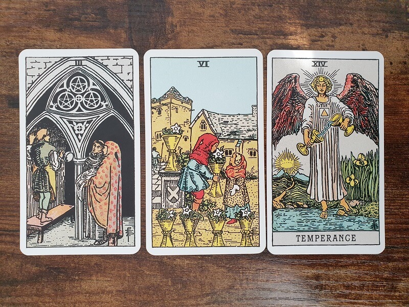 Psychologisches Tarot für empathisches Abgrenzen: 3 Tarotkarten auf einem Holztisch zum Thema Angst vor Kritik und Meinungen anderer überwinden