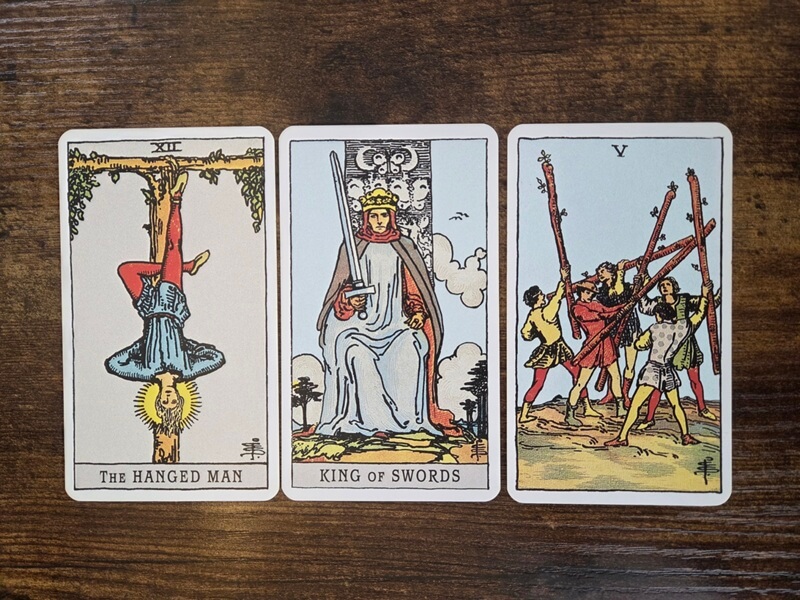 Psychologisches Tarot für empathisches Abgrenzen: 3 Tarotkarten auf einem Holztisch zum Thema „Gesund abgrenzen durch bewusste Konfrontation“