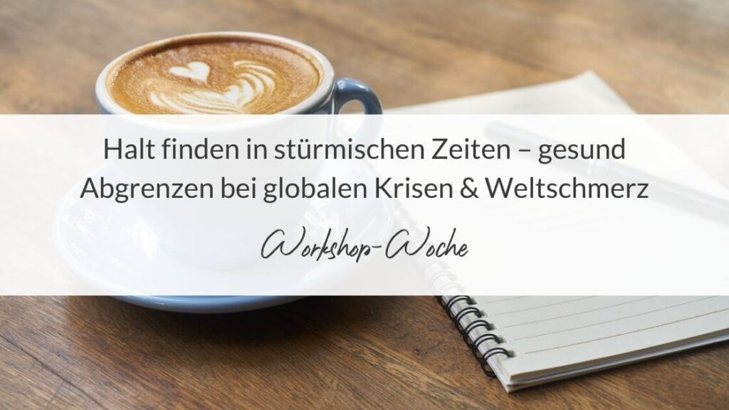 Textbild: Tasse Cappuccino mit Herzmotiv und Notizbuch auf Holztisch. Text: Halt finden in stürmischen Zeiten – gesund Abgrenzen bei globalen Krisen & Weltschmerz. Darunter handschriftlich: Workshop-Woche.